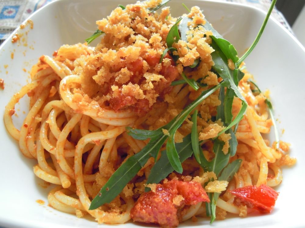 Spaghetti in padella con la nduja impiattati con pomodori rucola e mollica